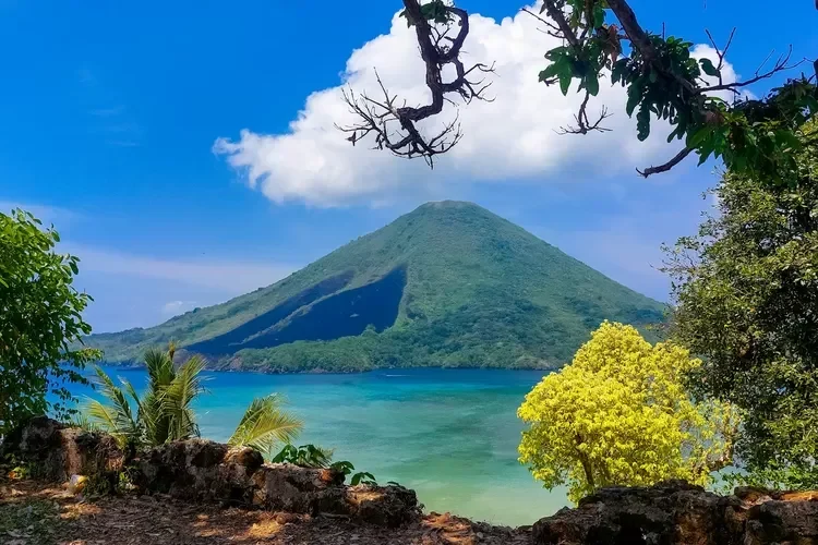 Pemandangan indah Gunung Api Banda, laut biru jernih, dan pepohonan rindang.