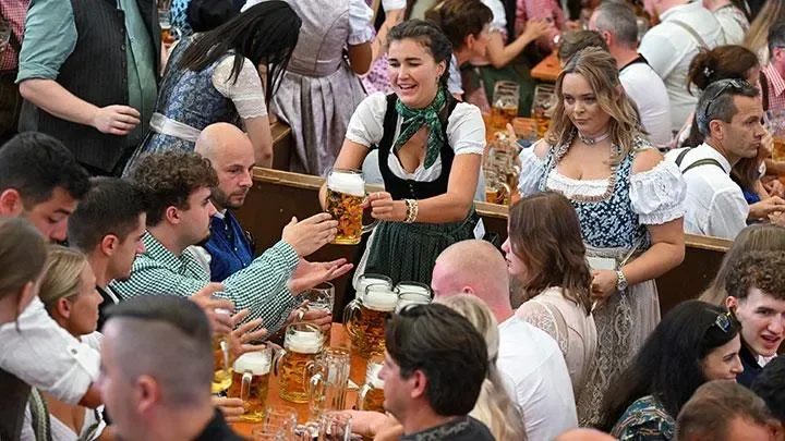 Pelayan menyajikan bir kepada pengunjung di tenda pesta Oktoberfest yang ramai.