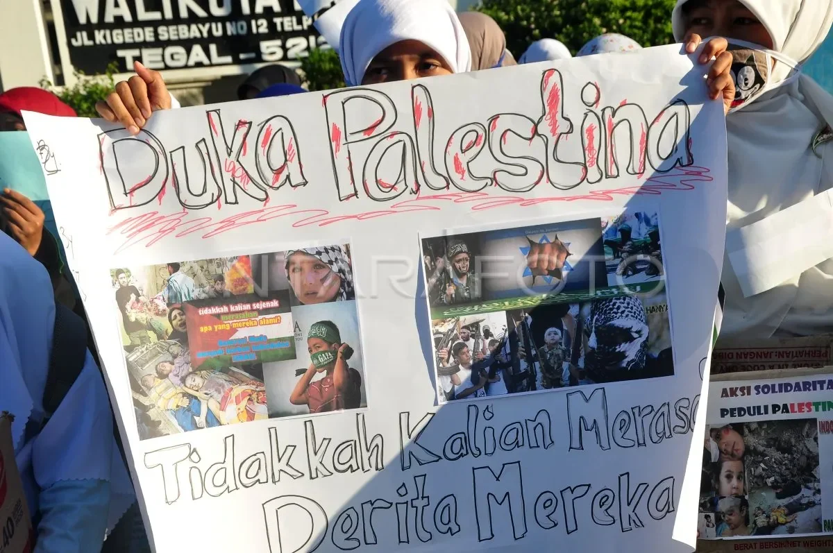 Pengunjuk rasa membawa spanduk 'Duka Palestina' menampilkan foto-foto penderitaan di Gaza.