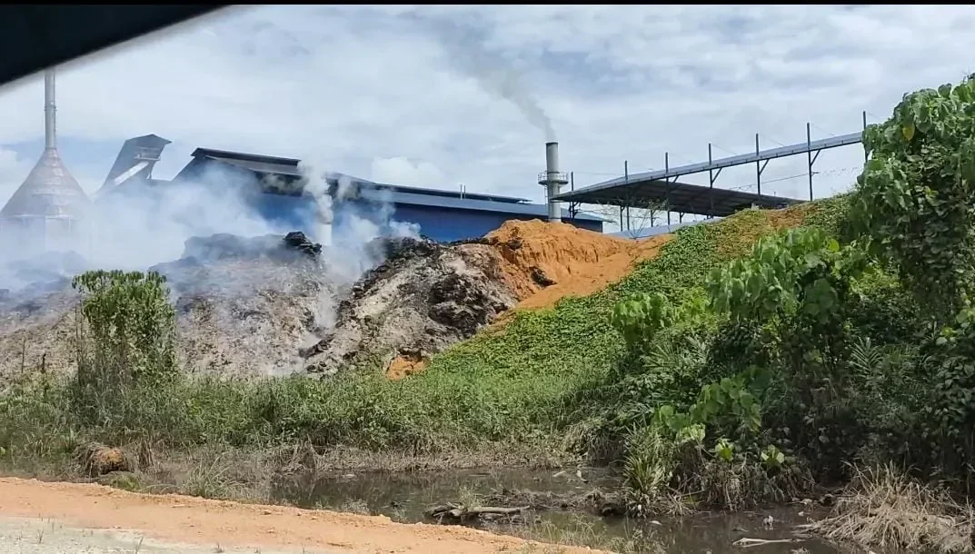 Pabrik berasap dan tumpukan limbah, simbol praktik bisnis yang tidak etis.