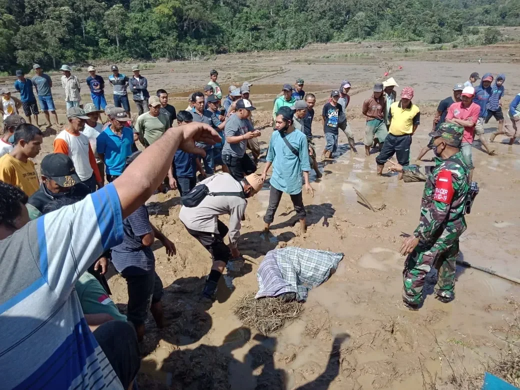 Sekelompok orang berkerumun di lahan berlumpur, beberapa tampak berdiskusi serius.