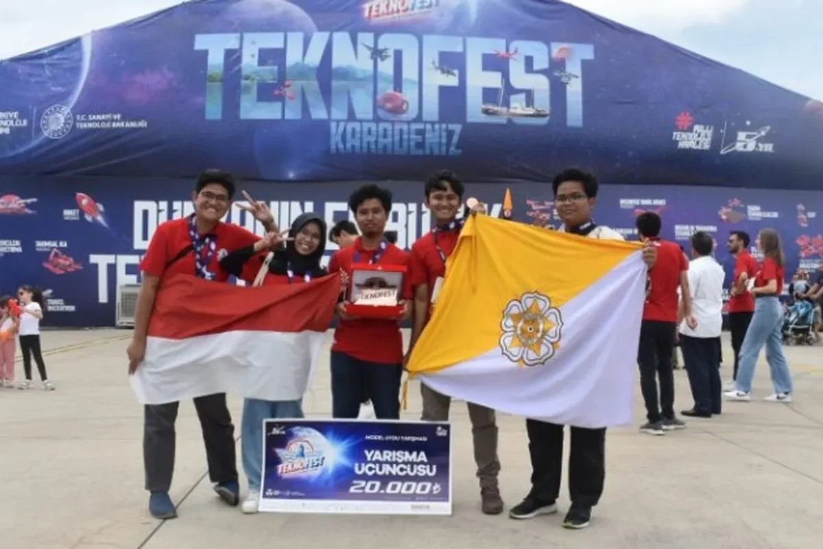 Mahasiswa Indonesia bangga berpose dengan bendera Merah Putih dan piala di Teknofest.