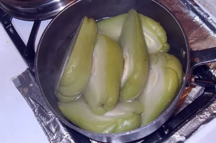 Labu siam segar dipotong dan direbus dalam panci di atas kompor.