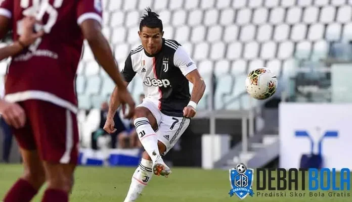 Cristiano Ronaldo menendang bola dalam seragam Juventus, fokus dan penuh semangat.