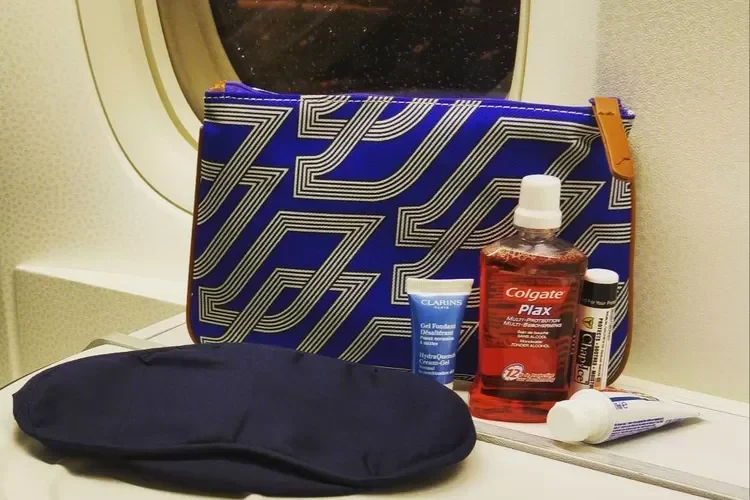 Amenity kit maskapai dengan perlengkapan mandi, masker mata, di dekat jendela pesawat.