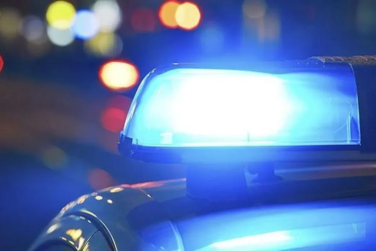 Lampu strobo biru menyala terang di atas kendaraan pada malam hari.