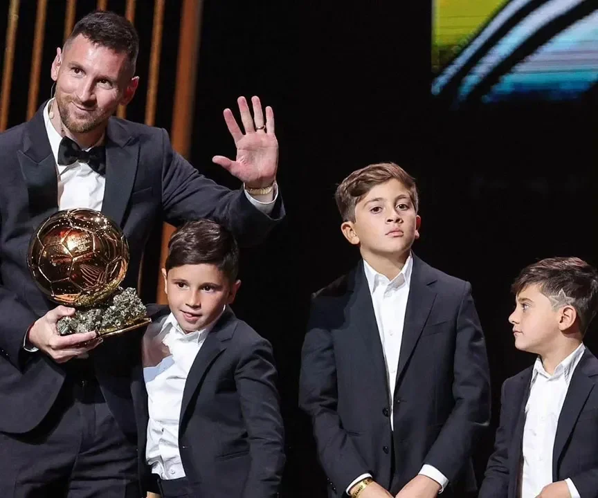 Lionel Messi bersama anak-anaknya memegang trofi Ballon d'Or.