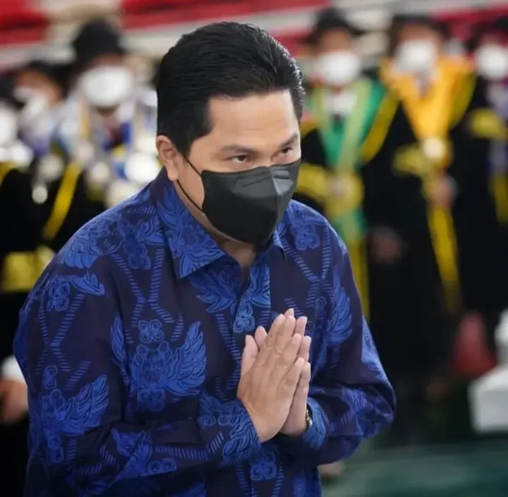 Erick Thohir kenakan masker dan baju bermotif, tangkupkan tangan.