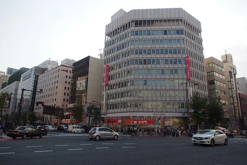 Jalanan ramai di Jimbōchō, Tokyo, dengan gedung perkantoran, toko, mobil, dan pejalan kaki.