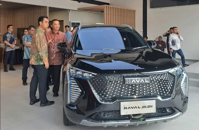 Mobil Haval Jolion hitam dipamerkan, orang-orang di sekitarnya melihat.