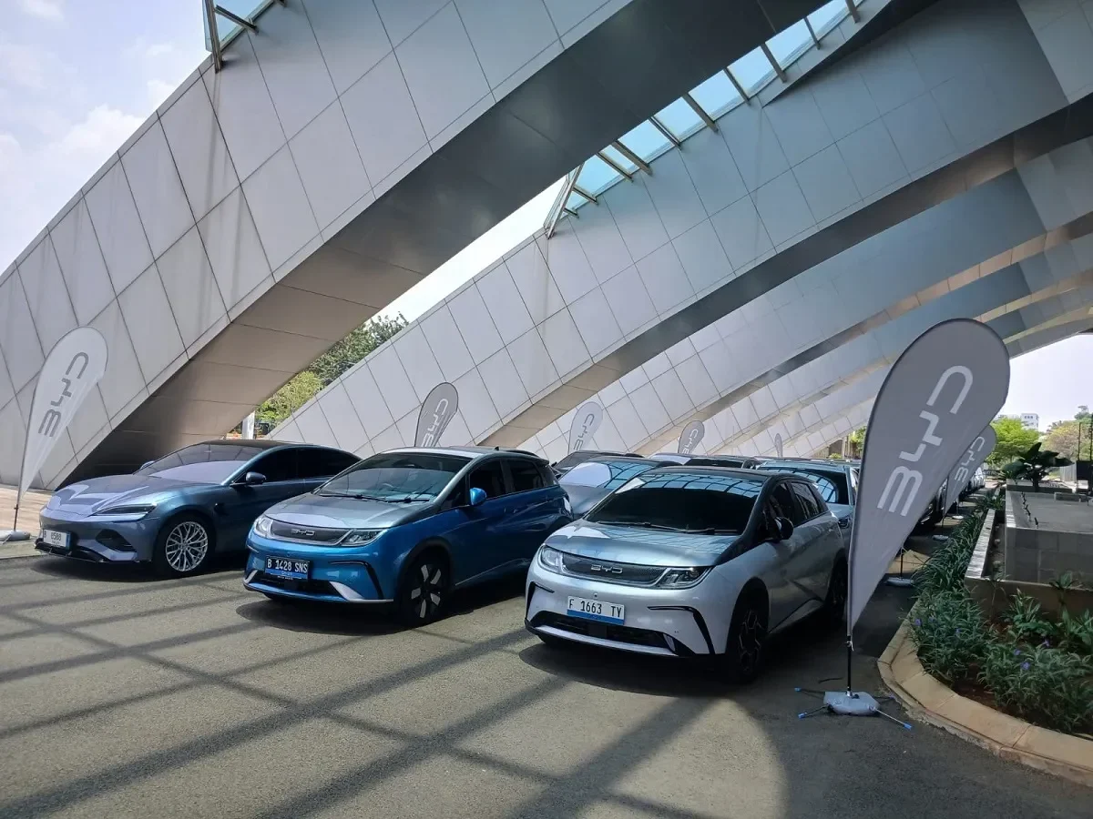 Jajaran mobil listrik BYD berbagai model terparkir rapi dengan bendera merek BYD.