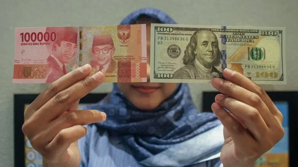 Tangan memegang uang Rupiah Indonesia dan Dolar Amerika Serikat.