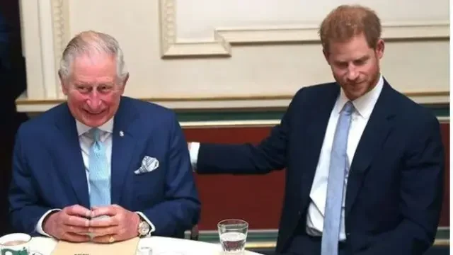 Raja Charles III tersenyum saat Pangeran Harry meletakkan tangan di bahunya.