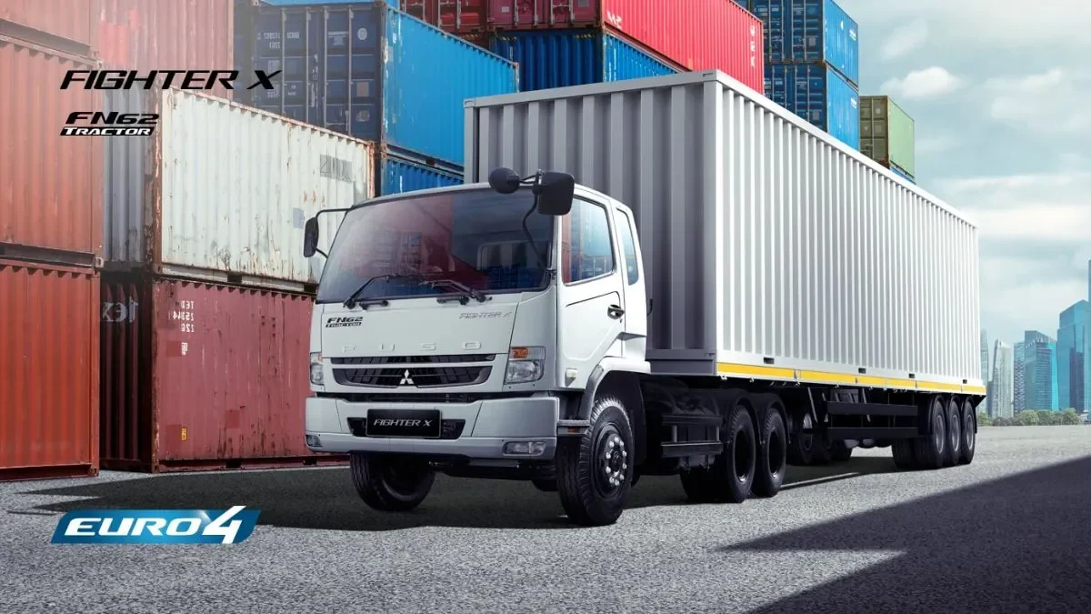 Truk tractor head Mitsubishi Fuso Fighter X baru di area logistik dengan tumpukan kontainer.