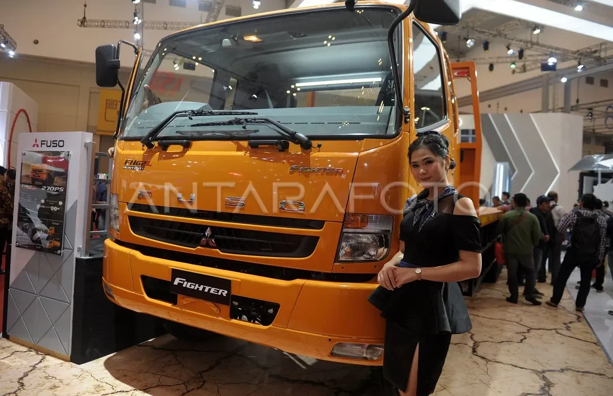 Truk Fuso Fighter X FM65F Tractor Head 4x2 berwarna oranye dengan model wanita di depannya.
