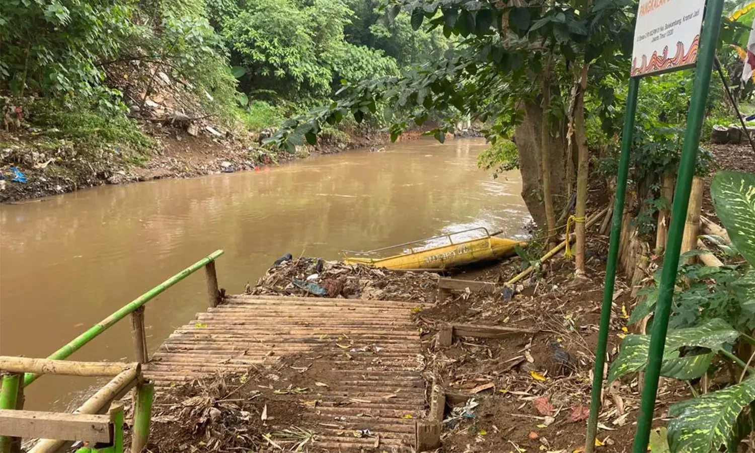 Dermaga bambu menuju sungai Ciliwung dengan vegetasi hijau di Eco Edu Wisata Jakarta.