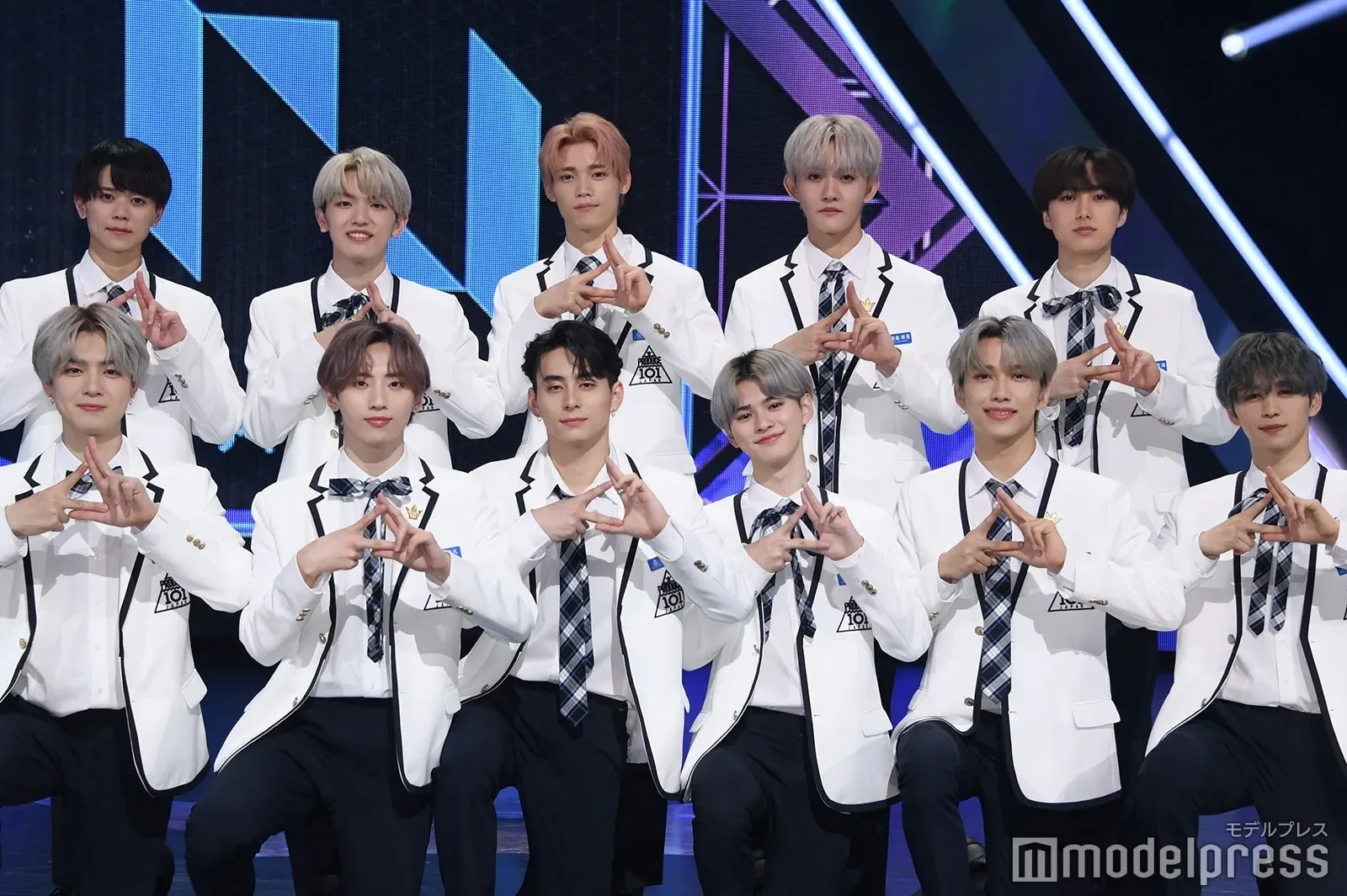 Sekelompok pria muda mengenakan pakaian putih menampilkan gestur tangan.