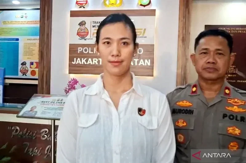 Petugas kepolisian bersama seorang wanita di depan logo Polres Jakarta Selatan.