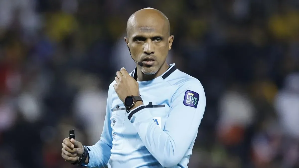 Ofisial Konfederasi Sepak Bola Asia (AFC) mengenakan seragam, memegang peluit di lapangan.