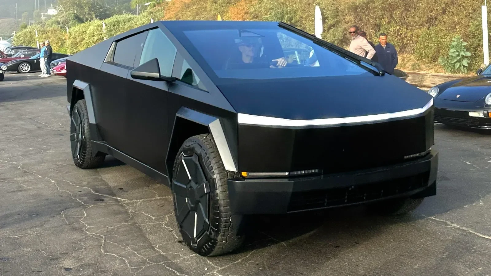 Tesla Cybertruck hitam dengan desain futuristik di jalan aspal retak.