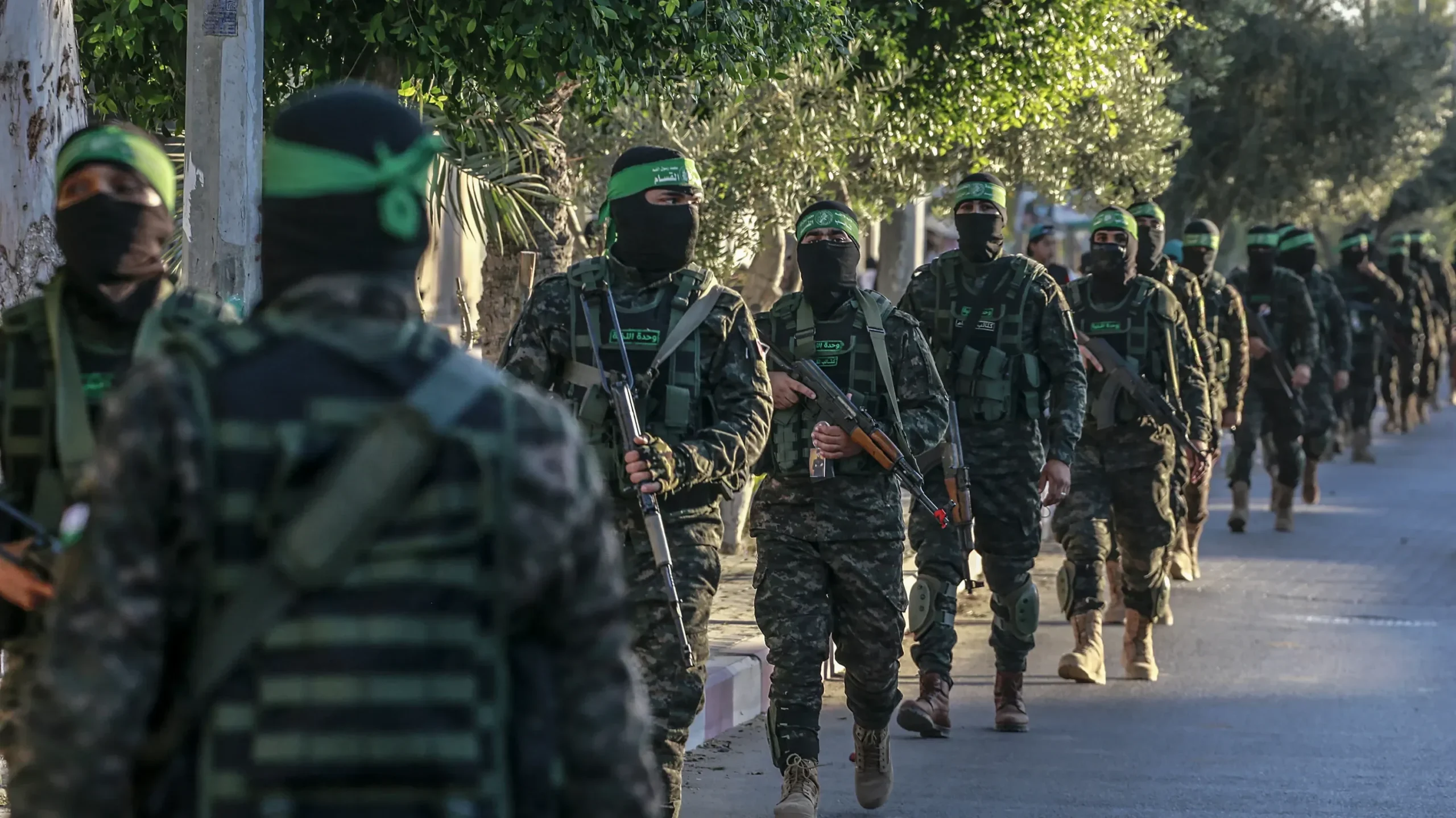 Anggota bersenjata Hamas dengan balaclava dan ikat kepala hijau berbaris di Gaza.