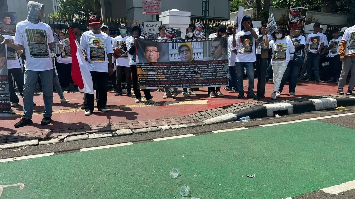 Protes menuntut kejelasan kerja, dengan demonstran membawa spanduk menolak ancaman PHK massal.