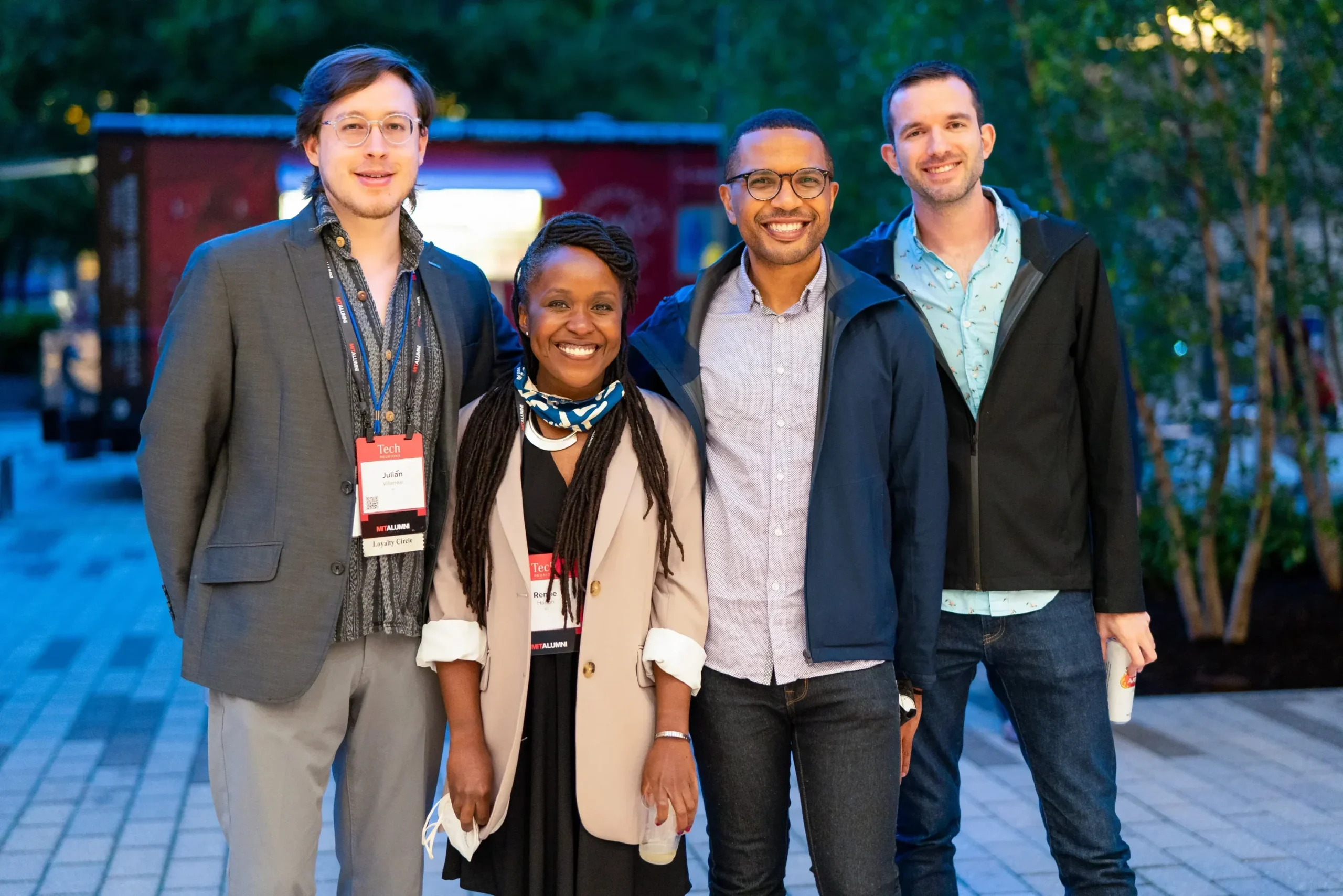 Empat orang tersenyum berpose bersama di sebuah acara, memakai ID lencana.