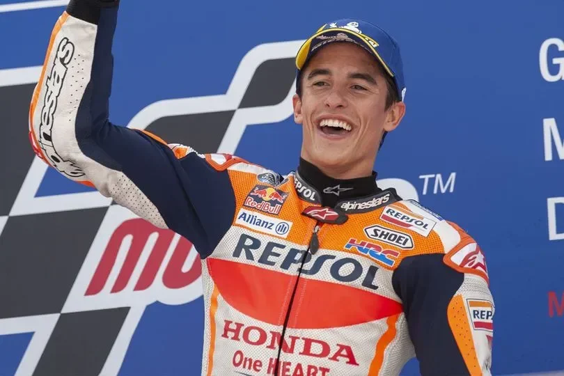 Marc Marquez merayakan kemenangan dengan penuh kegembiraan, mengangkat tangannya di udara.