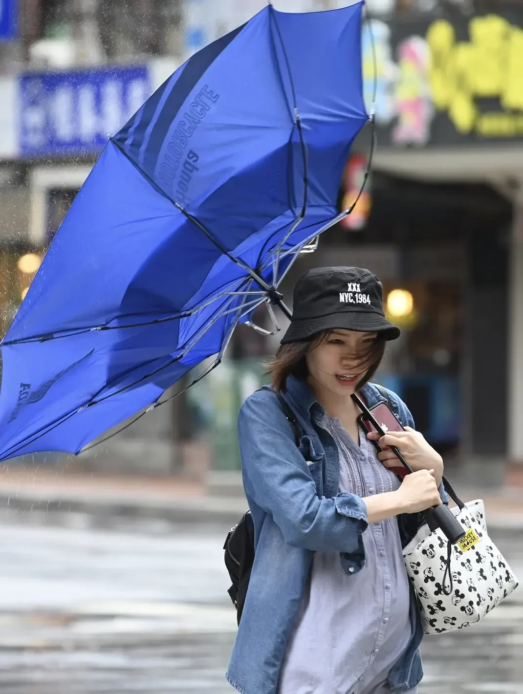 Wanita berjuang dengan payung terbalik di tengah angin kencang dan hujan deras.