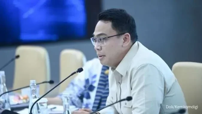 Angga Raka Prabowo, mengenakan kemeja dan kacamata, berbicara di sebuah rapat.