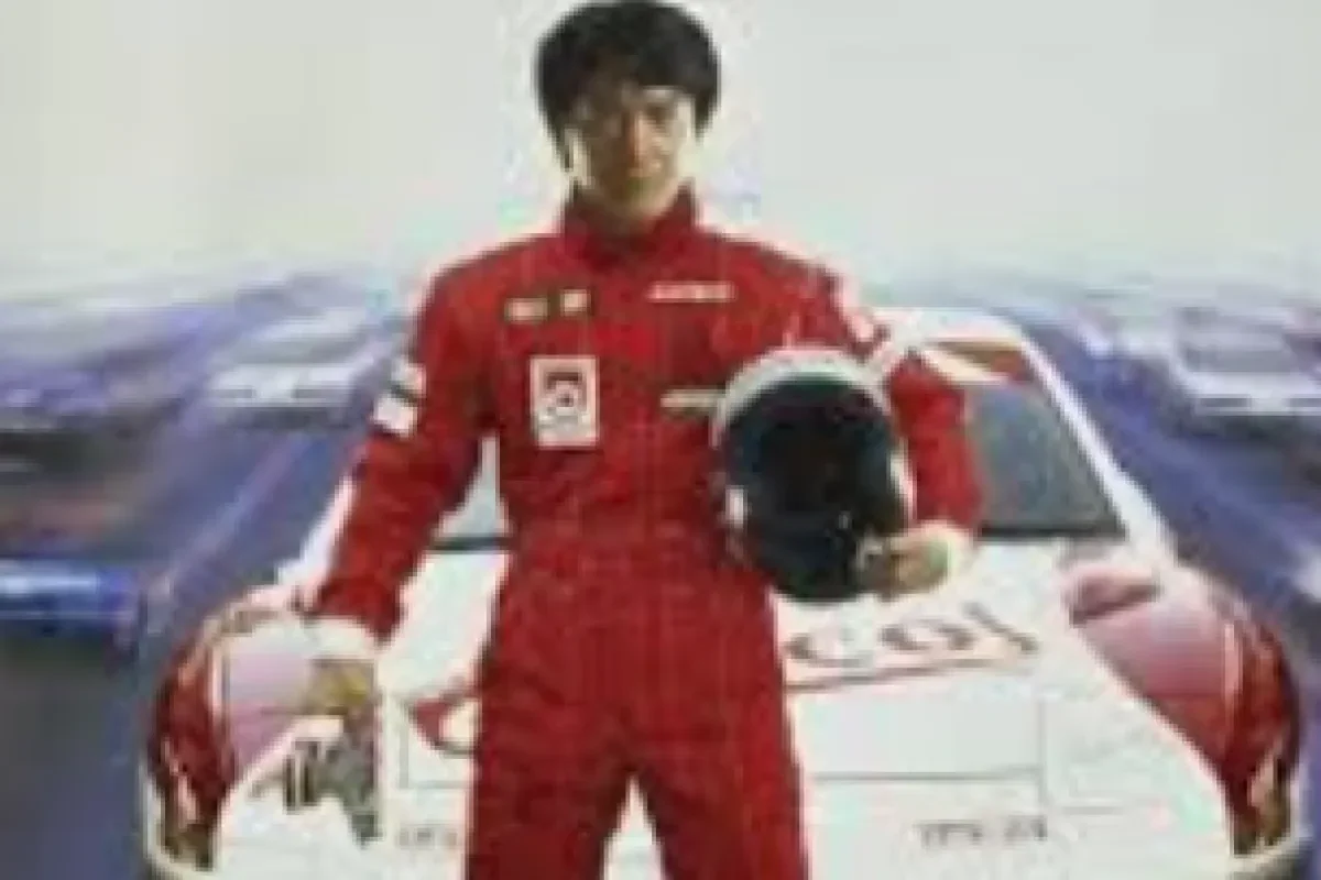 Jackie Chan dalam busana pembalap memegang helm di depan mobil balap.