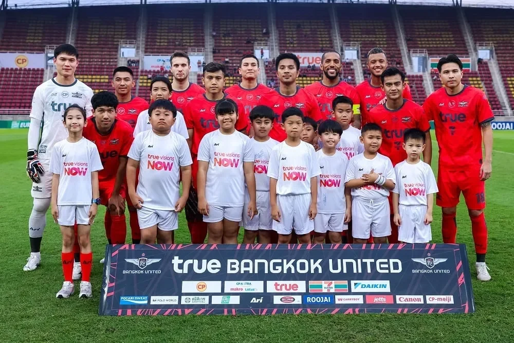 Pemain Bangkok United berpose bersama anak-anak di lapangan sebelum pertandingan.