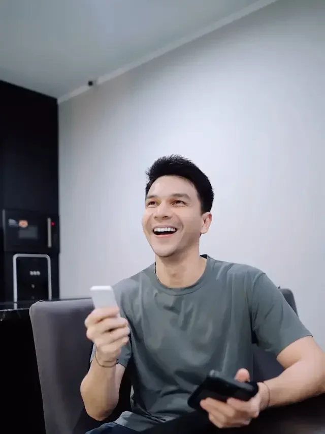 Aktor Jonathan Frizzy tertawa sambil memegang ponsel dan remote, terjerat kasus vape etomidate.