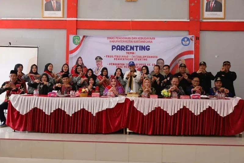 Kelompok orang-orang berpose di depan spanduk acara parenting PAUD di Kutai Kartanegara.