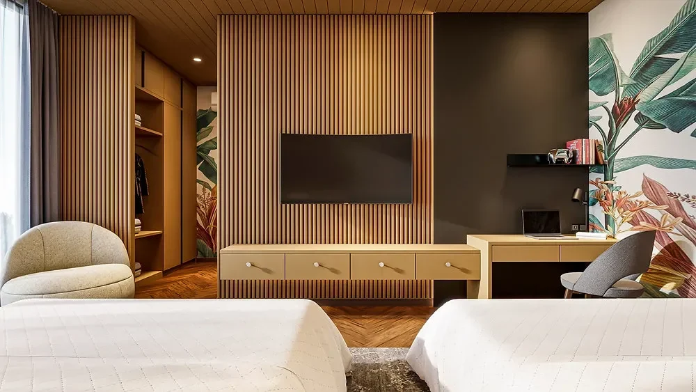 Kamar hotel modern dengan TV layar datar, meja kerja, dan dekorasi dinding floral.
