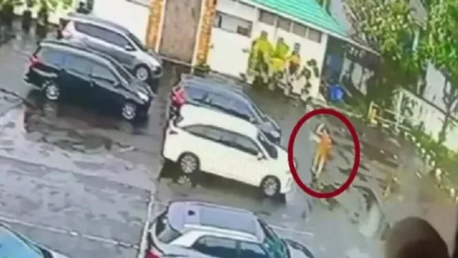 Sosok diduga korban tergeletak di parkiran, dikelilingi mobil dan orang-orang.