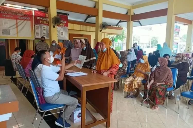 Warga sedang mengantre untuk administrasi bantuan sosial di kantor desa.