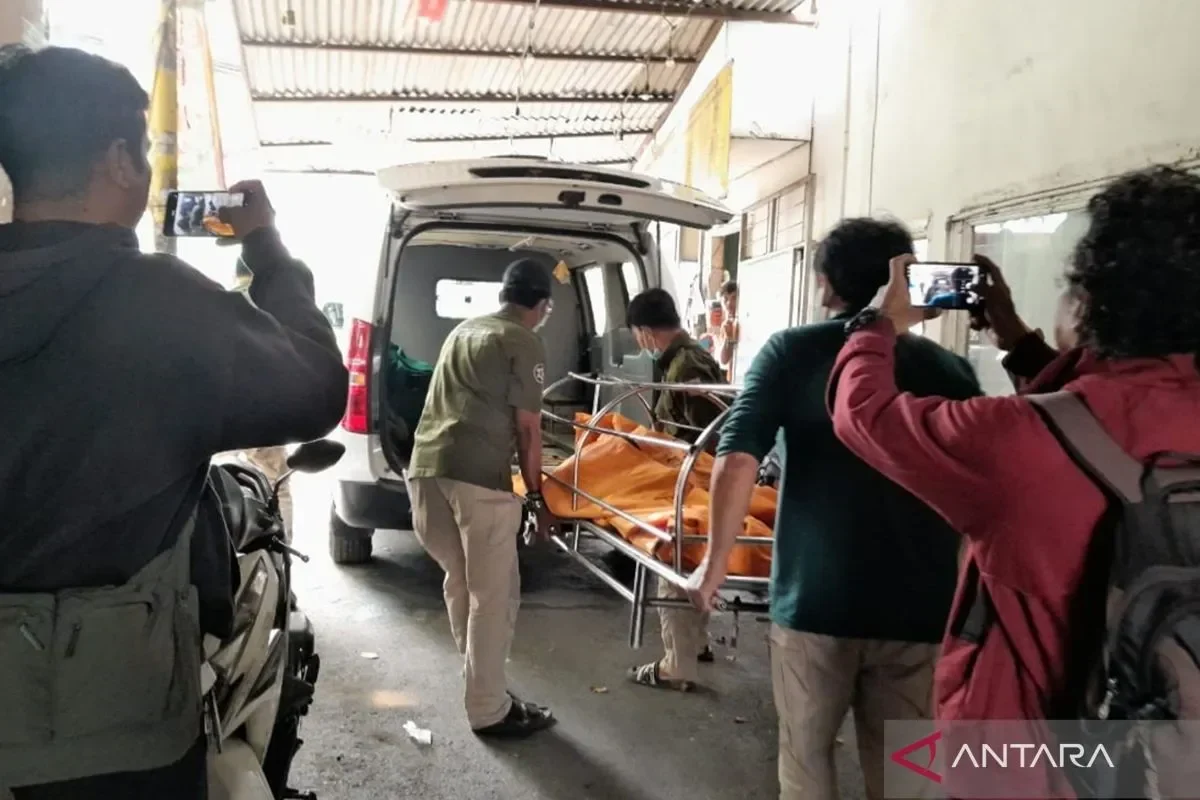 Petugas memindahkan jenazah korban pembunuhan ke ambulans, disaksikan warga merekam.