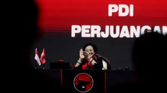 Megawati Soekarnoputri di podium PDI Perjuangan, bertepuk tangan dan tersenyum.
