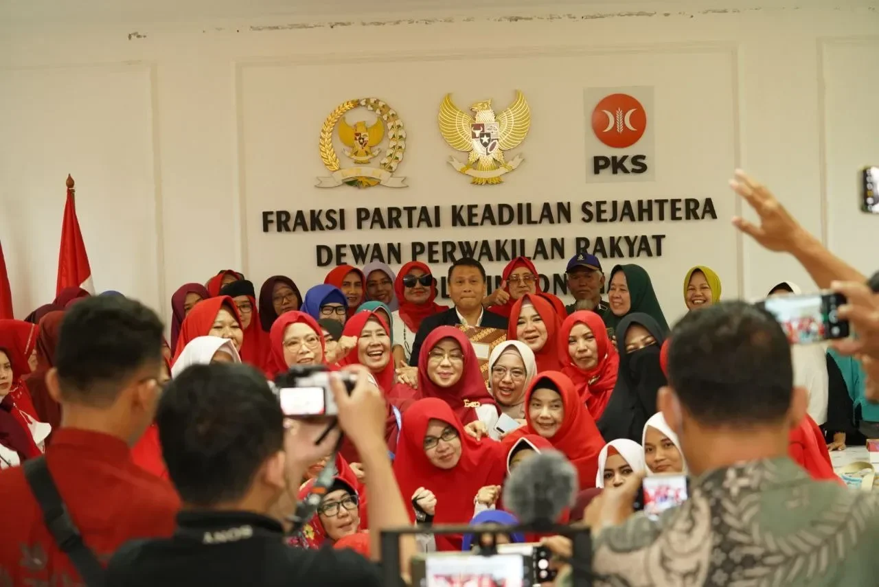Sekelompok warga berhijab merah antusias berfoto di depan spanduk Fraksi PKS DPR RI.