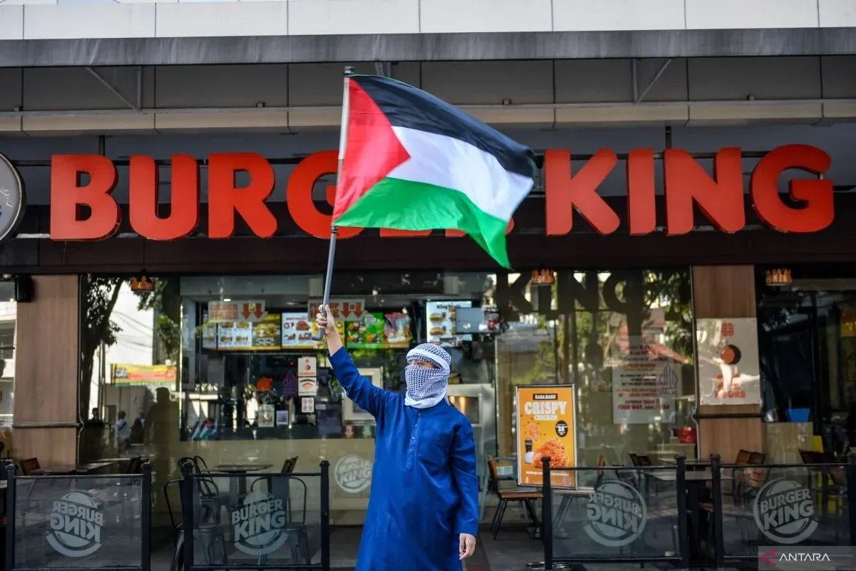 Seseorang mengibarkan bendera Palestina di depan restoran Burger King.