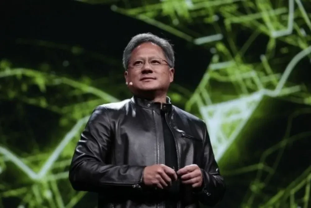 Jensen Huang, CEO Nvidia, kenakan jaket kulit, latar belakang hijau abstrak.