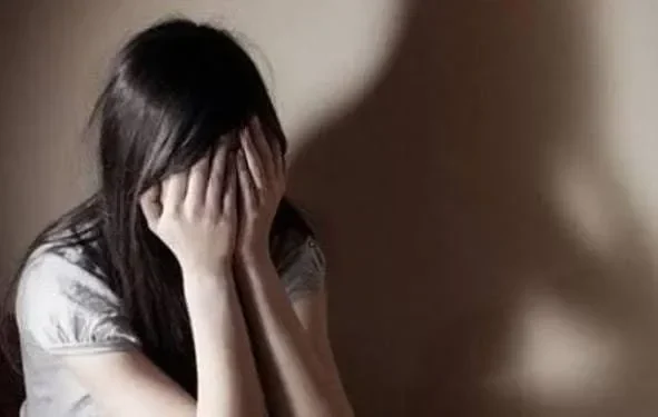 Ilustrasi: Seorang perempuan menutupi wajahnya dengan tangan, menunjukkan kesedihan dan trauma.