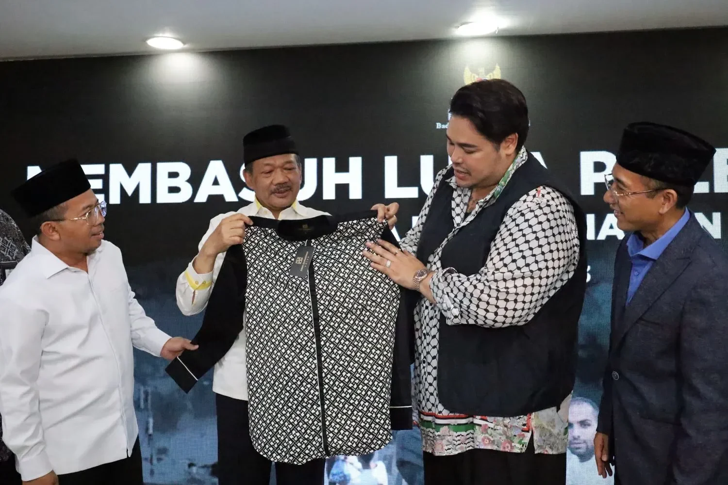 Ivan Gunawan menunjukkan pakaian berkerah dengan motif kotak-kotak kepada beberapa pria.