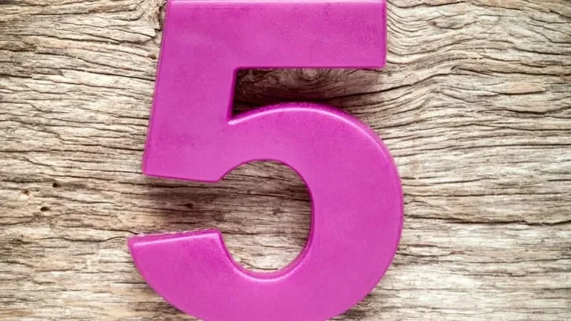 Angka lima berwarna magenta cerah pada tekstur permukaan kayu.