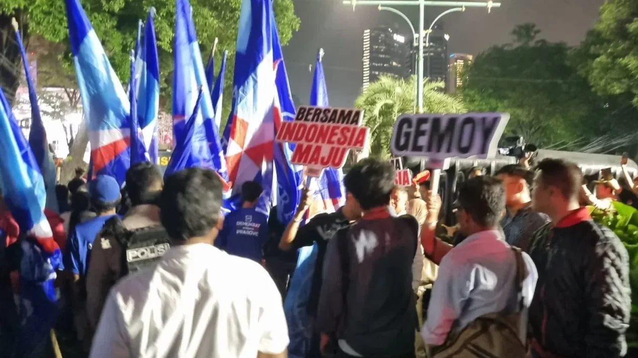 Massa pendukung dengan bendera biru dan spanduk politik meramaikan suasana di Jakarta.