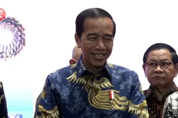 Presiden Joko Widodo tersenyum mengenakan batik biru di sebuah acara formal.