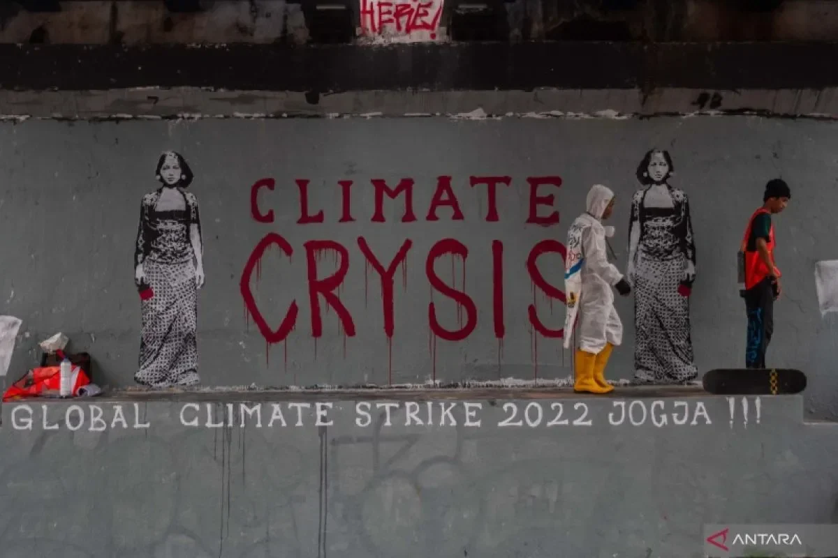 Mural "Climate Crisis" dengan figur manusia di sampingnya.