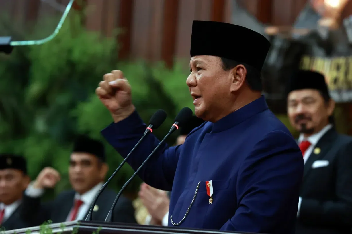 Prabowo Subianto berpidato di podium dengan gestur tangan mengepal ke atas.