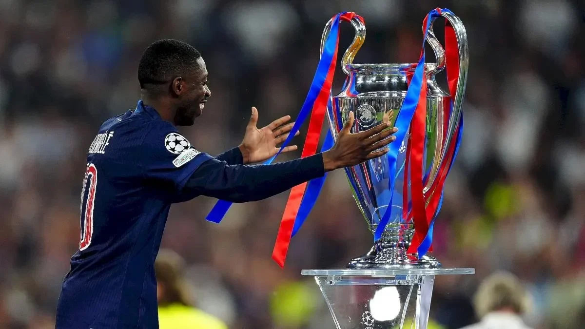Ousmane Dembele tersenyum menatap trofi, mengenakan jersey PSG.